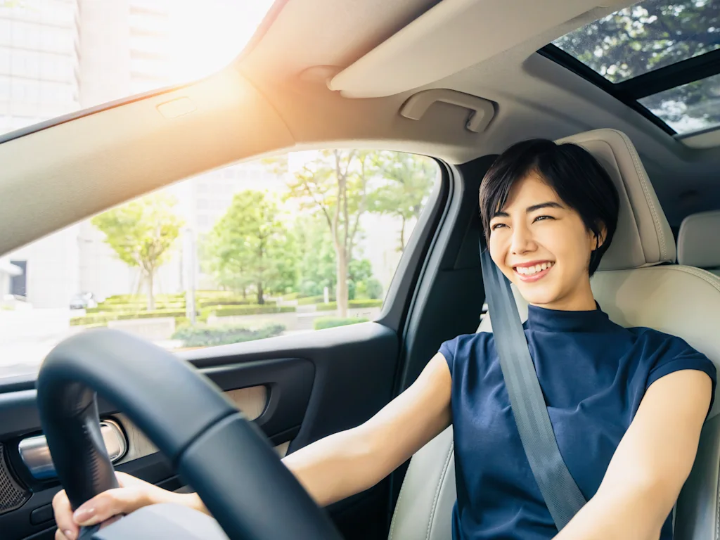 A woman enjoying driving her brand new car.