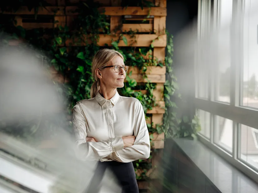 A businesswoman looks confidently out her office window.