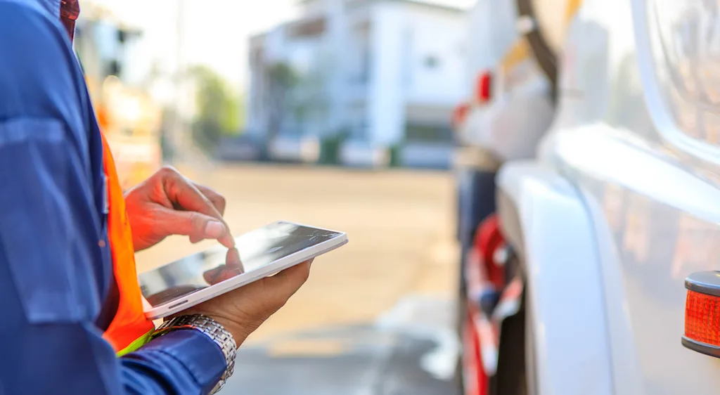 Hands typing on tablet next to truck