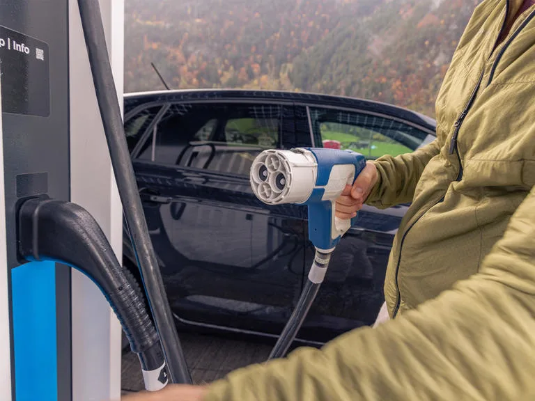 man plugging in ev charger charging station
