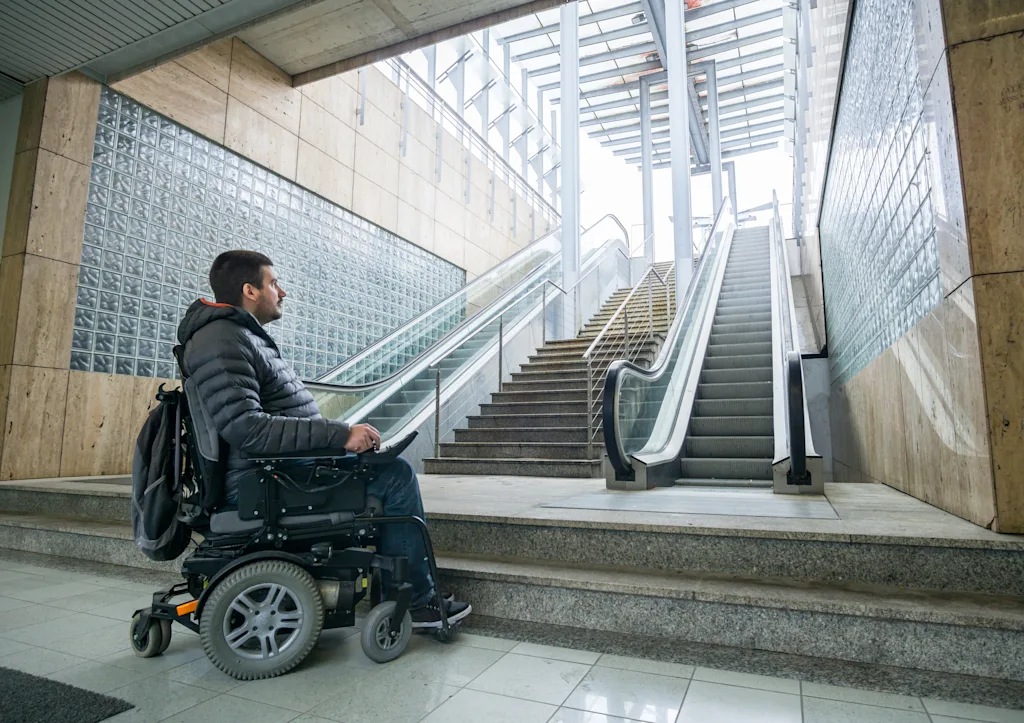 disabled man on wheelchair in front of escalator and staircase blog